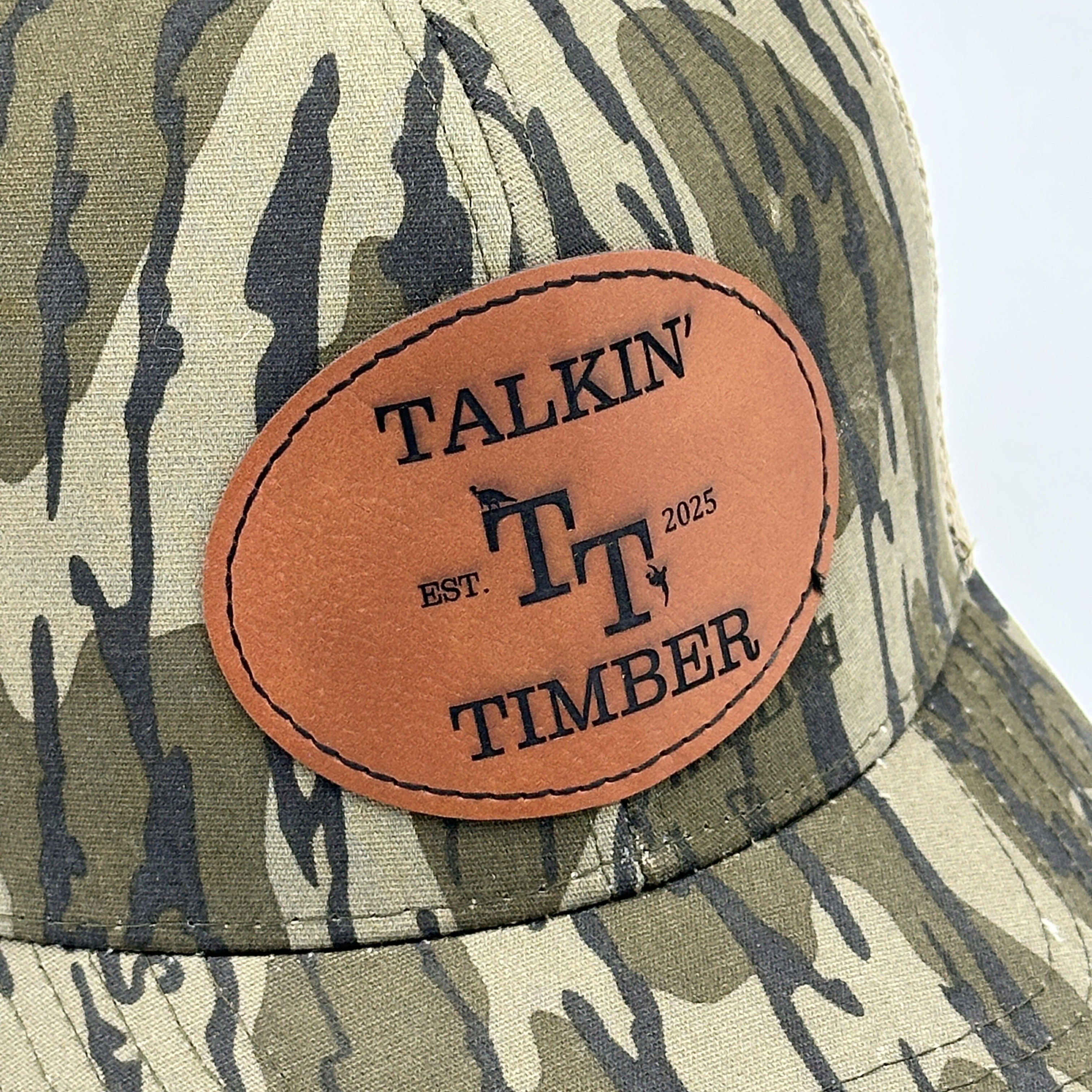 Close up patch view of Mossy Oak Bottomland™ mesh back trucker hat with adjustable snapback closure and iconic camo pattern for hunting and outdoor activities.