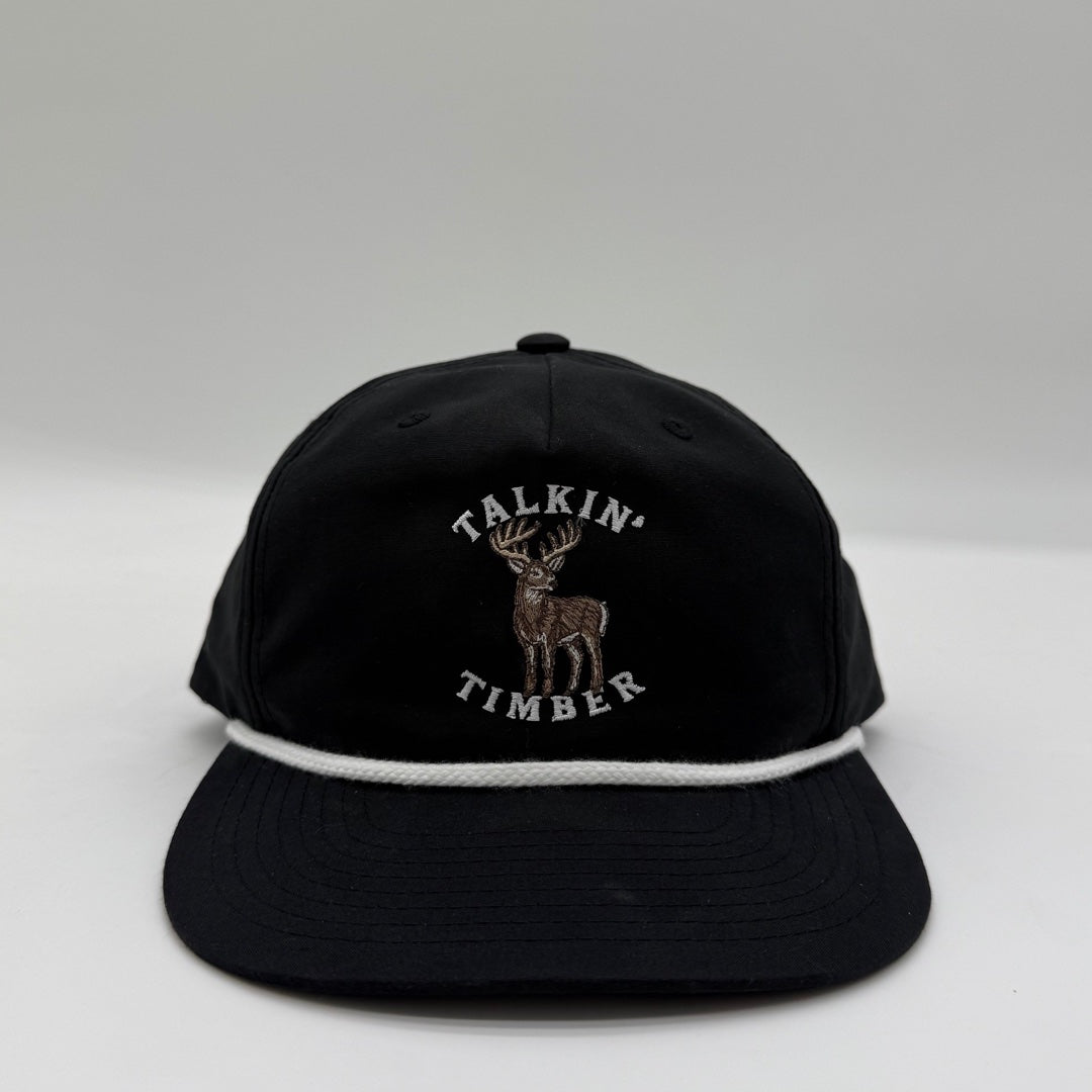 Front view of the Talkin’ Timber Black Buck Hat with whitetail buck embroidery, a black crown and bill, and white rope.