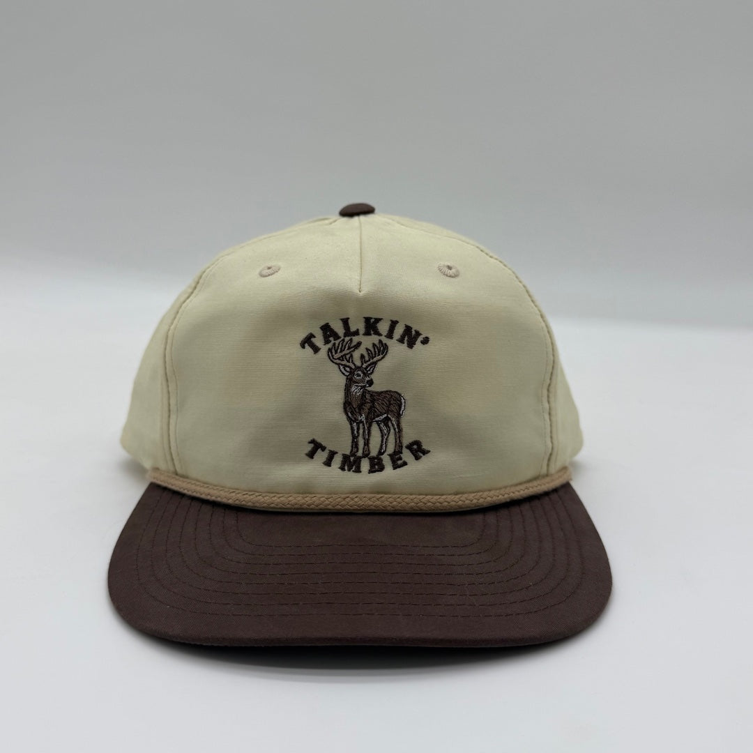 Front view of the Talkin’ Timber Big Buck Cream Hat with whitetail buck embroidery, a cream crown, brown bill, and tan rope.