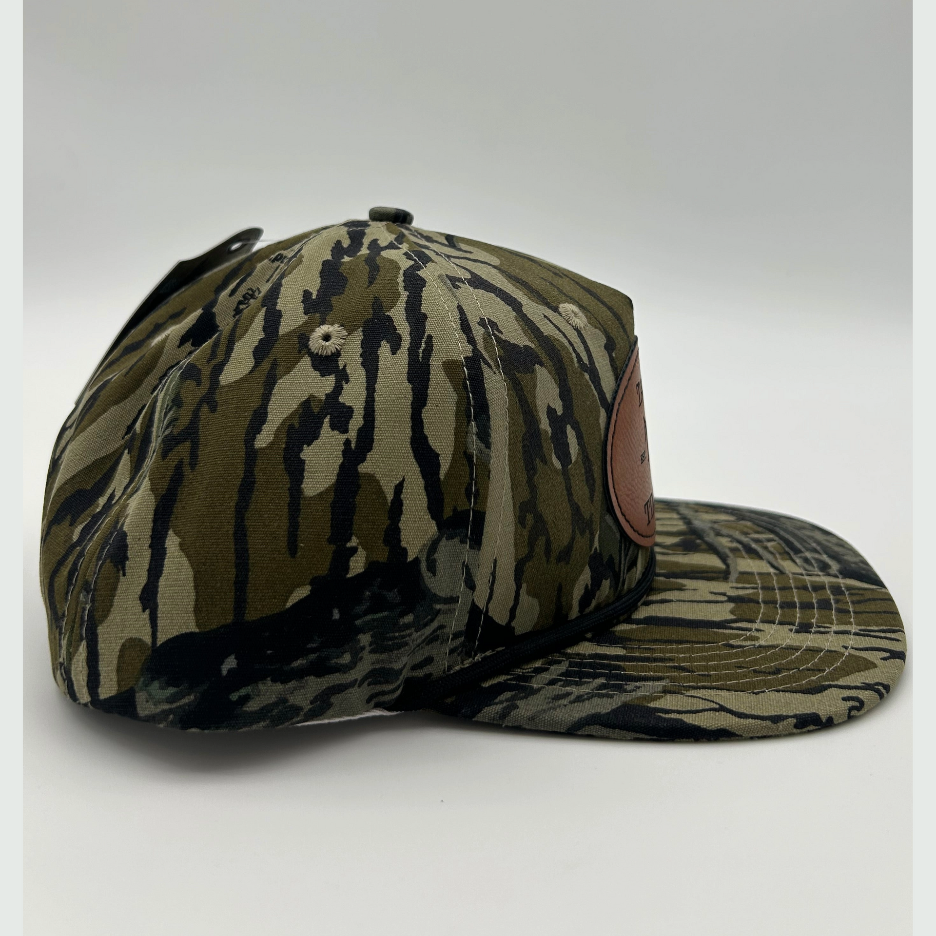 Side view of Mossy Oak Treestand™ rope hat with genuine leather patch and camouflage design, ideal for ducks, turkey, and deer hunters.